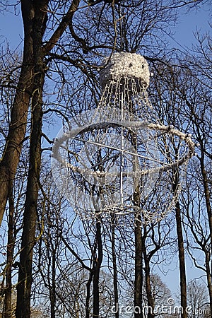 Close up of white unusual interesting shape lantern or lamp hanging on trees with almost no leaves. Lamp made of Stock Photo