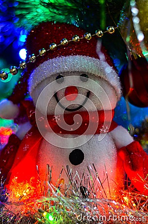 Close-up of a winter white toy snowman with Christmas tinsel in the background Stock Photo