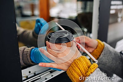 Close up of woman buying coffee and taking a paper cup from the barista seller`s hands. Street food and drinks, contactless Stock Photo