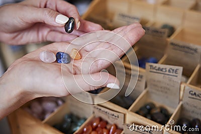 Close Up Of Woman Choosing Healing Crystals In Shop Stock Photo