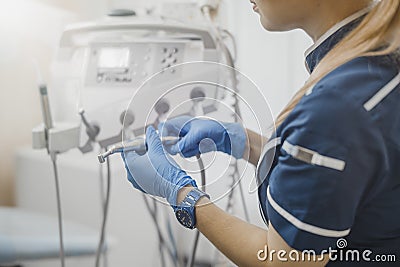 Close up of woman dentist in blue uniform checking dental equipment. Stock Photo