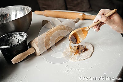 Female hand puts a filling in a pie dough Stock Photo