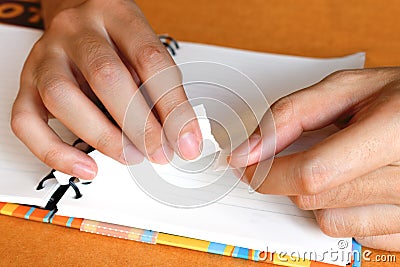 Close up woman hand ripping or tear white paper at notebook Stock Photo