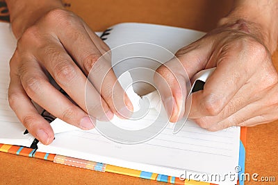 Close up woman hand ripping or tear white paper on notebook Stock Photo