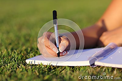 Close up of a woman hand writing on a notebook outdoor Stock Photo