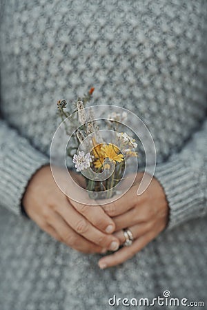 Close up of woman hands holding floreal flowers natural bouquet from field and meadow. People and nature connection. Grey Stock Photo