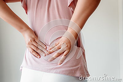 Close-Up of Woman Hands is Massaging Her Waist on Gray Background, Young Adult having Backache After Home Work. Stock Photo