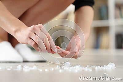 Woman hands picking up broken glass on the floor at home Stock Photo