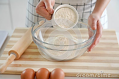 Close-up of woman hands pouring the flour into the bowl. Increasing price of wheat, flour and bread. Homemade bread preparation. Stock Photo