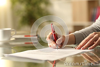 Woman signing document with pen on a desk at home Stock Photo