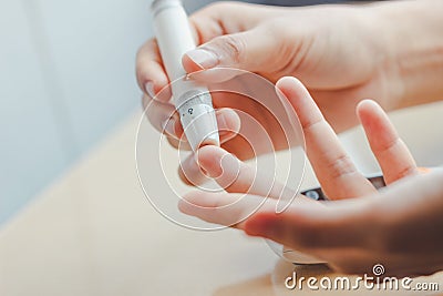 Close up of woman hands using lancet on finger to check blood sugar level by Glucose meter using as Medicine. Stock Photo