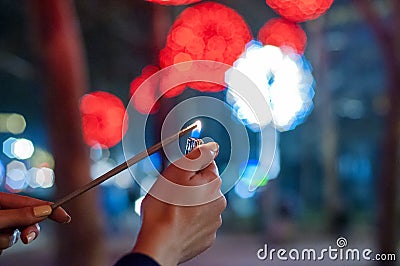 Close up of woman holding sparkler on the street. Closeup of Girl with Sparkle. Stock Photo