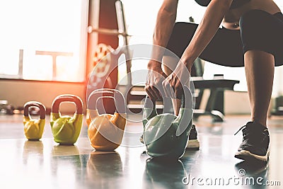 Close up of woman lifting kettlebell like dumbbells in fitness sport club gym training center with sport equipment near window Stock Photo