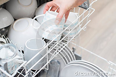 Close Up Of Woman Loading Crockery Into Dishwasher Stock Photo