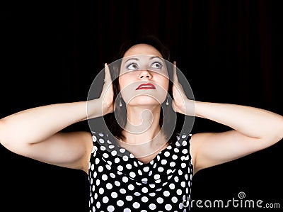 Close-up woman looks straight into the camera on a black background. laughing woman covers his ears with his hands Stock Photo