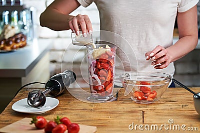 Close up of woman making strawberry smoothie. Healthy eating, cooking and summer refreshment concepts Stock Photo