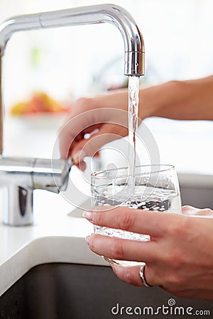 Close Up Of Woman Pouring Glass Of Water From Tap In Kitchen Stock Photo