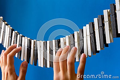 Close-up of a woman`s hand playing the imaginary piano made from clothes pins on blue paper background Stock Photo