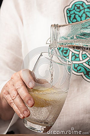 Close-up of woman`s hand serving tonic in a glass with lemon, Stock Photo