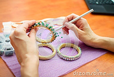 Close-up woman`s hands, decorating bracelets with colorful shiny rhinestones Stock Photo