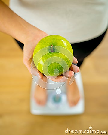 Close up of woman on scale holding fresh green apple in Diet and healthy lifestyle concept Stock Photo