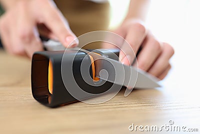 Woman sharpening knife with special knife sharpener Stock Photo