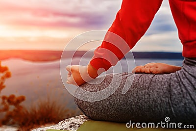 Close-up of the woman sitting in lotus position and meditating on the rock. Stock Photo