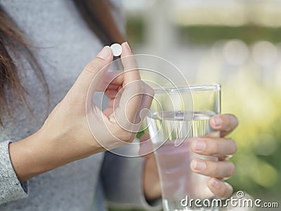 Close up of woman taking in pill with bokeh background. Stock Photo