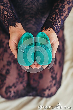 Close up woman touching holding baby shoes Stock Photo