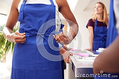 Close Up Of Woman Tying Apron Taking Part In Cookery Class In Kitchen Stock Photo