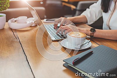 Close up of woman typing keyboard on laptop in coffee shop. People and technology concept. Freelance and Lifestyle theme. Stock Photo