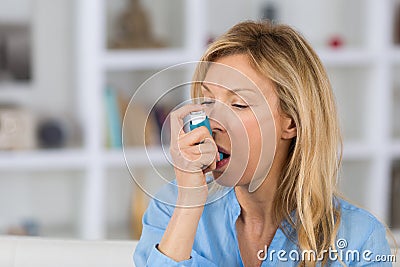 Close-up woman using asthma inhaler in living-room Stock Photo