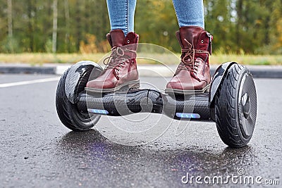 Close up of woman using hoverboard on asphalt road. Feet on electrical scooter outdoor Stock Photo