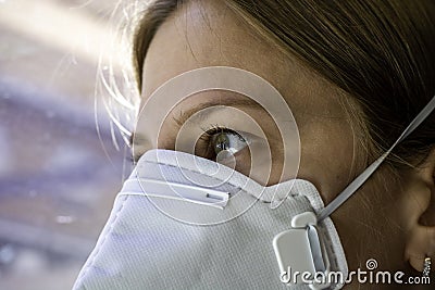 Close up woman wearing a FFP3 face mask looking outside. Disposable respirator protective mouth filter mask Stock Photo