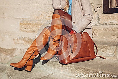 Close up of woman wearing stylish orange boots leather skirt holding purse outdoors. Spring fashion accessories clothes Stock Photo