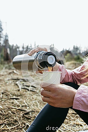 Close-up of a woman& x27;s hands pouring coffee from a thermos in the forest. Rest at nature. Hiking Stock Photo