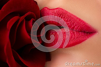 Close-up of womans lips with fashion red glossy makeup. Lips with lipstick closeup. Beautiful woman lips with rose. Stock Photo
