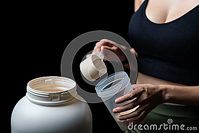 Close up of women with measuring scoop of whey protein, jar and shaker bottle, preparing protein shake Stock Photo