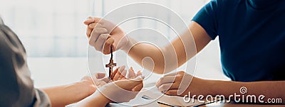 Close-up women prayer deliver wooden cross to young believer. Burgeoning. Stock Photo