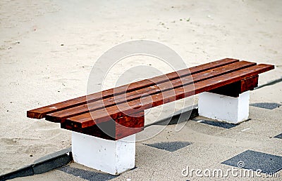 Bench surrounded by sand on the esplanade footpath near the sea . Resting place on the beach Stock Photo