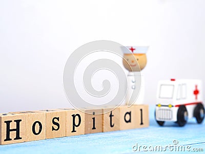 Close up wooden blocks wording Hospital and small white ambulance model on blue wood background Stock Photo