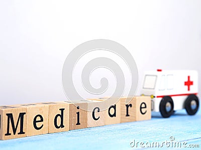 Close up wooden blocks wording Medicare and small white ambulance model on blue wood background Editorial Stock Photo