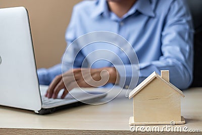 Close up wooden House model, Businessman using laptop. housing purchase, Property, real estate and insurance concepts Stock Photo