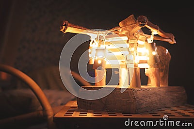 Close-up wooden lampshade with backlight and rocking chair in a poorly lit bedroom at night. Home comfort concept Stock Photo