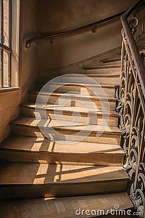 Close-up of wooden staircase on the sunlight and Nouveau style iron balustrade in Paris. Editorial Stock Photo