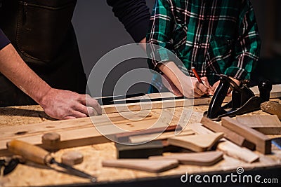 Close-up of the work of a man and a boy at a carpenter`s table, on the table are a plane, chisel, Board, workbench Stock Photo