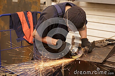 Close-up of worker cutting metal with grinder. Sparks while grinding iron. Stock Photo