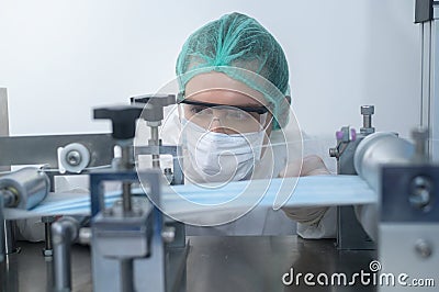 Close up of worker producing surgical mask in modern factory, Covid-19 protection and medical concept Stock Photo