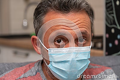 Close-up of worried man with sick eyes wearing surgical mask Stock Photo