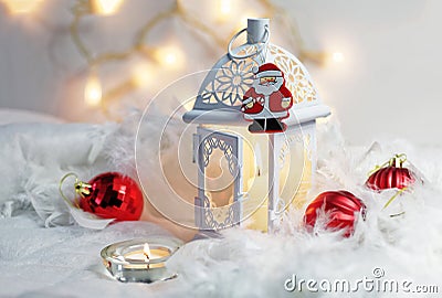 Close up of Xmas lantern with candles and red cozy balls. Christmas decoration on white fur. Shallow depth of field and bokeh. Stock Photo